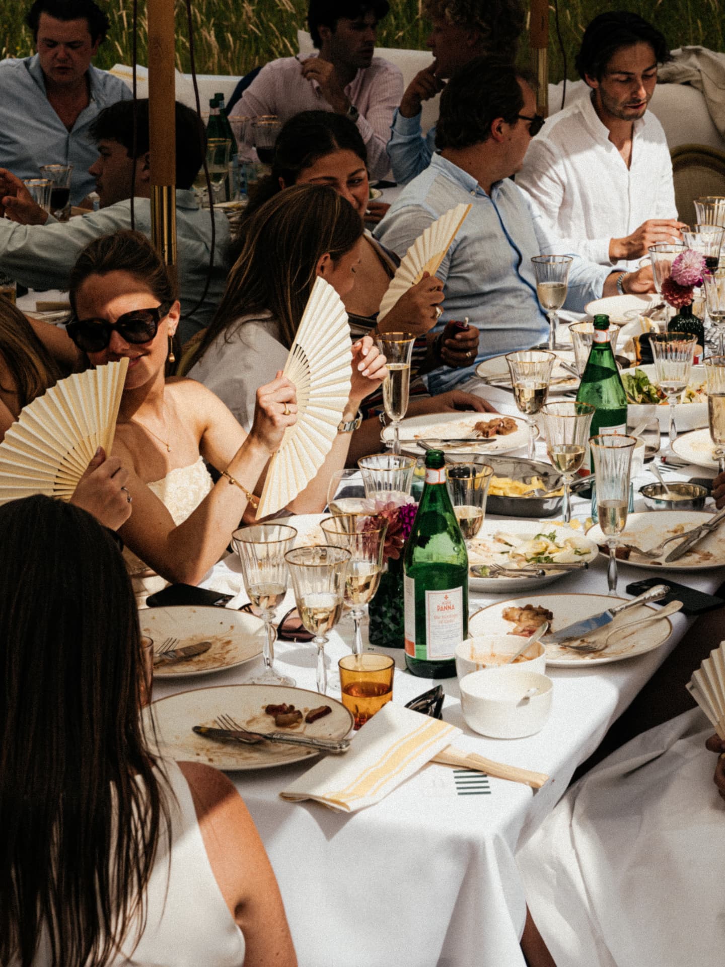 Gasten aan een lange gedekte tafel tijdens een zomers event